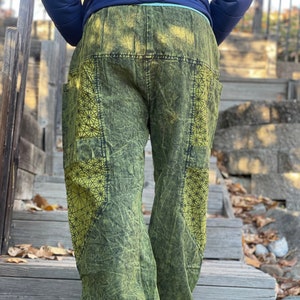 Może przedstawiać: Zielone spodnie z efektem sprania kwasem z geometrycznym wzorem na kieszeniach. Spodnie mają sznurek w pasie i luźny krój.