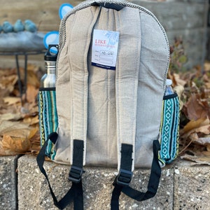 May include: A grey canvas backpack with black straps and a tag that says "Like International" and "MD-328". The backpack has a colourful patterned fabric on the sides.