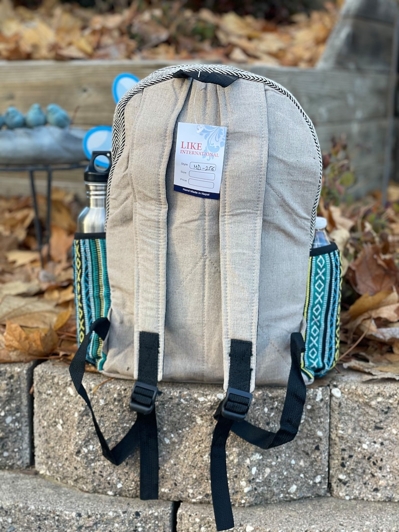 May include: A grey canvas backpack with black straps and a tag that says "Like International" and "MD-328". The backpack has a colourful patterned fabric on the sides.