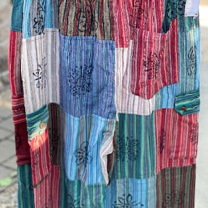 May include: Patchwork pants with a colorful striped pattern and floral designs. The pants have a drawstring waist and pockets.