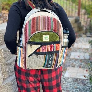 May include: A multi-coloured hemp backpack with a green patch that says "Hemp Love The Tree" and a zipped pocket. The backpack is being worn by a person wearing red and black checked trousers.