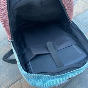 May include: A blue and white patterned backpack with a red and white chevron pattern on the top flap. The backpack is open and a black laptop is inside.