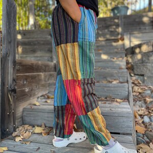May include: Patchwork pants with vertical stripes in shades of blue, green, yellow, red, and black. The pants are made of a soft, comfortable fabric and have a relaxed fit.