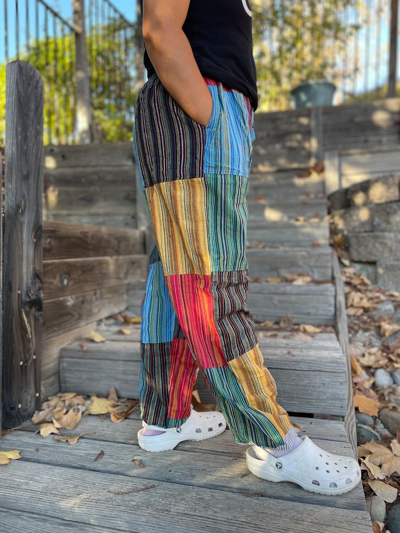 May include: Patchwork pants with vertical stripes in shades of blue, green, yellow, red, and black. The pants are made of a soft, comfortable fabric and have a relaxed fit.