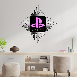 Peut inclure: Un autocollant mural noir et blanc représentant un logo PlayStation 5 stylisé avec une icône de manette rose à l'intérieur d'un circuit imprimé. L'autocollant est affiché sur un mur blanc dans un salon.