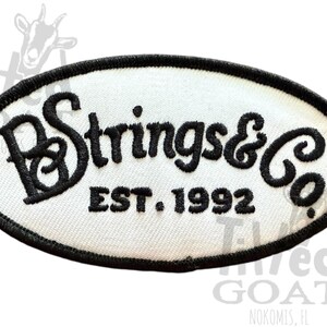 Pu&ograve; includere: Toppa ovale con sfondo bianco e testo ricamato nero. Il testo recita "PB Strings & Co" sopra "EST. 1992". La toppa ha un bordo nero. La toppa &egrave; probabilmente per abbigliamento o accessori.