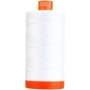 Pode incluir: Uma bobina de fio branco com um rótulo laranja que diz "Aurifil".