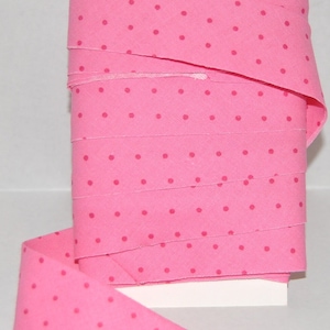 May include: Pink fabric ribbon with a white background and small pink polka dots.