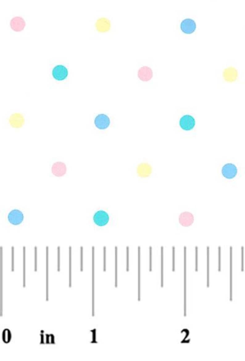 May include: White fabric with a repeating pattern of pastel-colored polka dots. The dots are pink, yellow, and blue. A ruler in inches is at the bottom of the image, showing measurements.