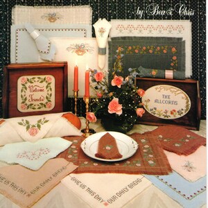 May include: A cross stitch pattern booklet titled "Candlelight & Roses" by Bea & Chris. The cover features a table setting with a white tablecloth, candles, and a floral centerpiece. The booklet includes patterns for various cross stitch designs, including "Welcome Friends", "The Allcorns", and "Give Us This Day Our Daily Bread".