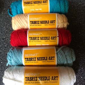 May include: Five spools of Bernat Tabriz Needle Art yarn in different colors: turquoise, cream, red, light blue, and white. Each spool is labeled with the brand name, yarn type, yardage, and fiber content. The yarn is 100% polyester and comes in 2 ounce spools.
