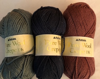 May include: Three balls of Patons Pure Wool Crepe DK yarn in green, navy blue, and brown.