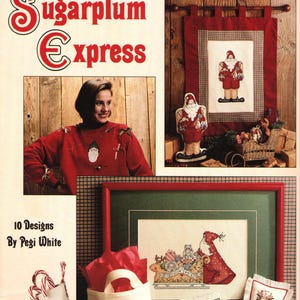 May include: A booklet titled "Sugarplum Express" with 10 cross-stitch designs by Pegi White. The cover features a red and white plaid background with a red and white cross-stitch design of Santa Claus. The booklet is from Leisure Arts and is leaflet number 2053.