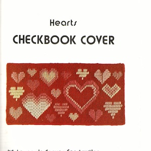 May include: A red canvas with a pattern of hearts in various shades of pink and white. The text "Hearts CHECKBOOK COVER" is at the top of the canvas. The text "with Lessons in Canvas Construction" is at the bottom of the canvas. The text "Joan Young" is signed in cursive at the bottom right corner of the canvas.