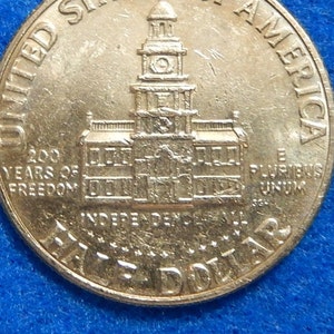 May include: A silver United States half dollar coin with the inscription "200 Years of Freedom" and a depiction of Independence Hall in Philadelphia, Pennsylvania. The coin also features the inscription "E Pluribus Unum" and "One Half Dollar".