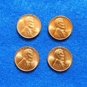 May include: Four copper-colored Lincoln pennies on a blue background. Each coin features a profile of Abraham Lincoln and the year of minting. The pennies are dated 1955, 1956, 1957, and 1958.