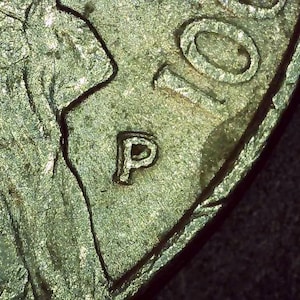 May include: Close-up of a silver coin with the letter "P" stamped on the side.