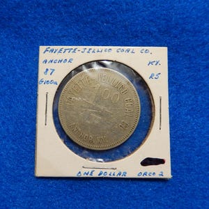 May include: A brass token with the text "FAYETTE-JELLICO COAL CO. ANCHOR KY. 100" and "ONE DOLLAR ORCO 2" on a white background.