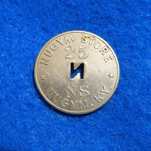 May include: A silver token with the text "NUGYM STORE 25" and "M.GYM. KY." around the edge. The token has a hole in the center in the shape of the letter "N".