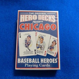 May include: A deck of "Hero Decks" playing cards featuring Chicago baseball players. The box is white with red and blue accents and the text "Chicago" in large letters. The cards show cartoon illustrations of baseball players.