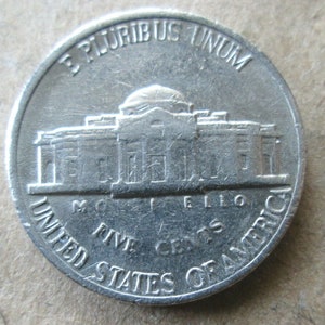May include: A silver US five-cent coin with the inscription "E Pluribus Unum" and "United States of America" around the edge. The coin features a depiction of the Lincoln Memorial.