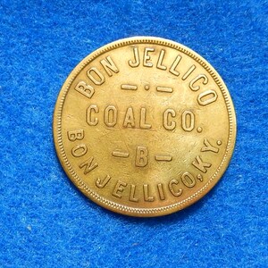 May include: A gold-colored metal token with the inscription "Bon Jellico Coal Co. Bon Jellico Co. Ky."