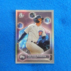 May include: A baseball card featuring Pete Crow-Armstrong of the Chicago Cubs. The card has a silver border and a holographic background with blue and purple accents. The player is wearing a Cubs uniform.