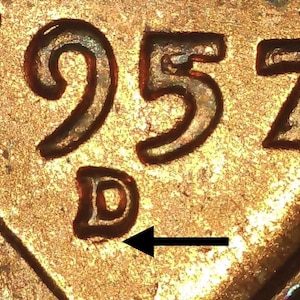 May include: Close-up of a copper penny with the year 1957 and the mint mark "D" stamped on the bottom.