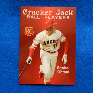 May include: A red, white, and blue Cracker Jack baseball card featuring Shohei Ohtani, a baseball player for the Los Angeles Angels. The card has the RC logo and the text "Cracker Jack Ball Players".
