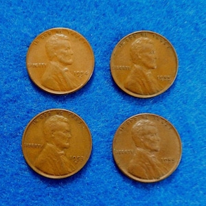 May include: Four copper-colored Lincoln pennies, each displaying a profile of Abraham Lincoln. The pennies are dated 1953, 1954, and two from 1955. The words "In God We Trust" and "Liberty" are visible on each coin.