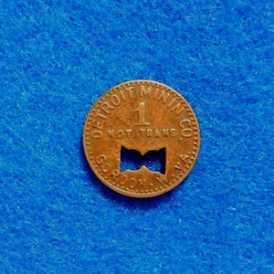 May include: A copper-colored token from the Detroit Mining Co. with the number 1 and the words "NOT TRANS" visible. The token has a unique cut-out design and the text "GORDON, VA" is also present.