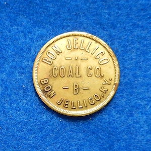 May include: A gold-colored metal token with the inscription "Bon Jellico Coal Co. Bon Jellico Ky."