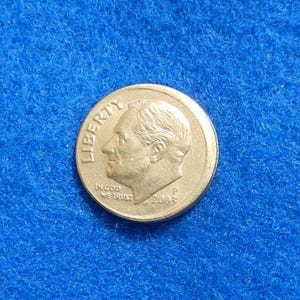 May include: A United States dime coin, featuring a profile of Franklin D. Roosevelt, the word "LIBERTY", and the inscription "IN GOD WE TRUST". The coin is dated 2003 and has a "P" mint mark.