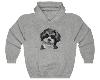Può includere: Una felpa con cappuccio grigio chiaro con una grafica in bianco e nero di un cane con occhiali da sole. Il cane ha un pelo soffice e sorride. La felpa ha un cappuccio con coulisse e una tasca a marsupio.