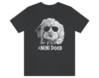 May include: A black t-shirt featuring a white graphic of a dog wearing sunglasses. The text "THE MINI DOOD" is below the dog.