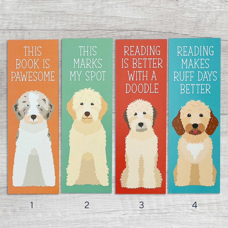 May include: Four colorful bookmarks featuring a doodle dog breed with different sayings. The first bookmark is orange with the text "This book is pawsome". The second bookmark is teal with the text "This marks my spot". The third bookmark is red with the text "Reading is better with a doodle". The fourth bookmark is blue with the text "Reading makes ruff days better".