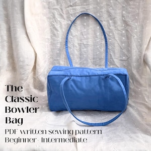 May include: A light blue bowler bag with matching handles, set against a white, textured background. The bag is rectangular with rounded corners. Text on the image reads "The Classic Bowler Bag" and "PDF written sewing pattern Beginner-Intermediate".