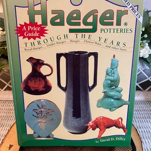 May include: A white ceramic mug with a black handle and the text "But First, Coffee" in a black, bold font. The mug is on a white surface.