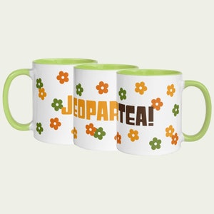 May include: Three white ceramic mugs with a light green rim. Each mug has a different floral pattern with orange and green flowers. The mugs have the text "Jeopartea!" printed on them.