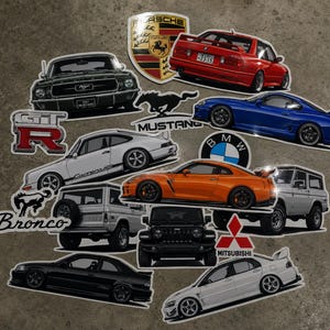 May include: A collection of automotive stickers featuring various car models including a black Ford Mustang, a red BMW, a blue Toyota Supra, a white Porsche Carrera RS, an orange Nissan GT-R, a silver Ford Bronco, a black Jeep, and a white Mitsubishi.