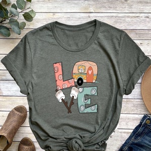 May include: A green t-shirt with a graphic of a camper van, marshmallows, and sticks forming the word "LOVE".