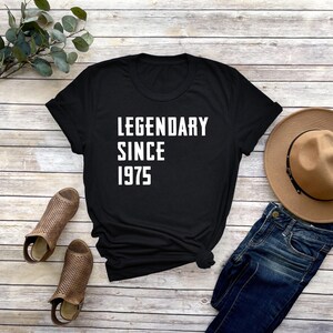 May include: Black t-shirt with white text that reads "Legendary Since 1975".