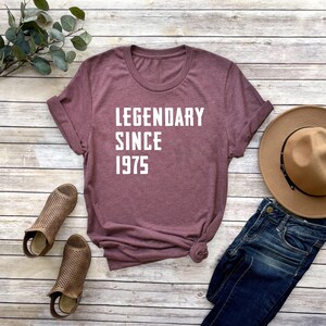 May include: A maroon t-shirt with white text that reads "LEGENDARY SINCE 1975".
