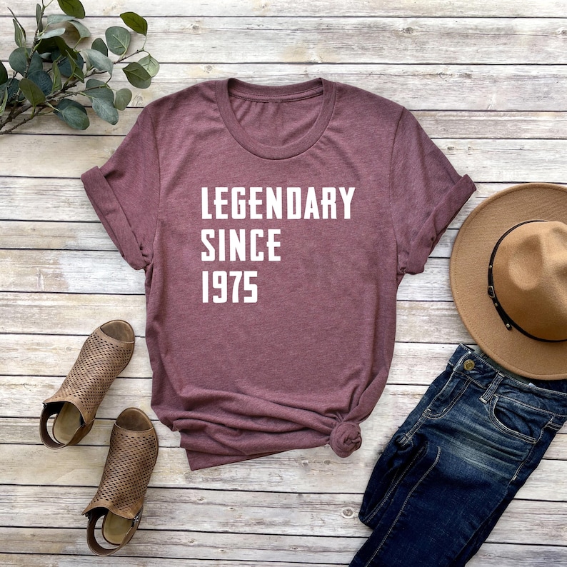 May include: A maroon t-shirt with white text that reads "LEGENDARY SINCE 1975".