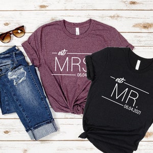 May include: Two t-shirts, one maroon and one black, with the text "est. MRS. 06.04" and "est. MR. 06.04.2021" printed on them.