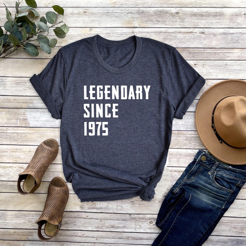 May include: A dark blue t-shirt with white text that reads "LEGENDARY SINCE 1975".