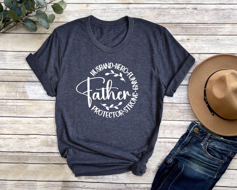 May include: A dark blue t-shirt with a white circle graphic that says "Father" with the words "Husband, Hero, Funny, Protector, Strong" around the circle.