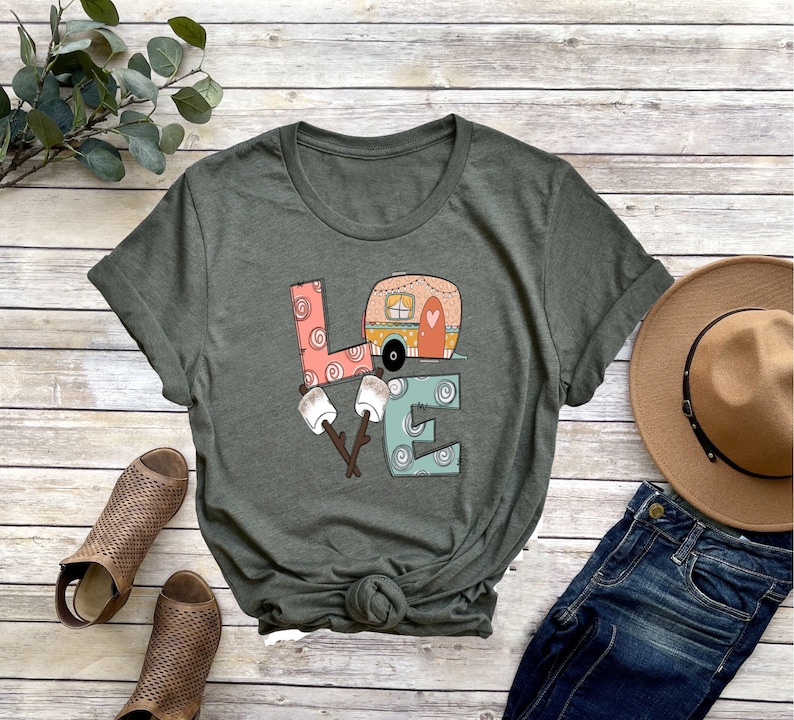 May include: A green t-shirt with a graphic of a camper van, marshmallows, and sticks forming the word "LOVE".
