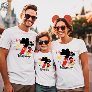 Op de afbeelding: Drie mensen dragen witte t-shirts met een Mickey Mouse-ontwerp. De shirts hebben een groot zwart nummer 7 met een rode en gele gradi&euml;nt, Mickey Mouse en de woorden "His 7th Birthday" en "My 7th Birthday".
