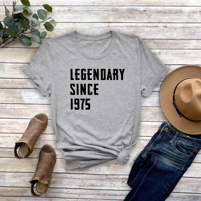 May include: Gray t-shirt with black text that reads "Legendary Since 1975".